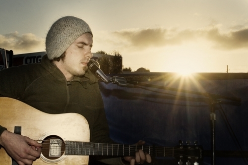 Josh Garrels playing guitar by the sea